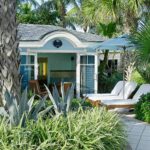 Wide angle shot of a beach bungalow with patio and lounge chairs.