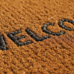 Close-up detail of a rustic natural coir welcome doormat with the word ‘welcome’ woven in dark fiber