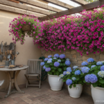 Cozy small terrace corner with blue hydrangeas in large white ceramic pots, trailing surfinias in pi