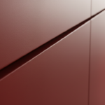 Macro close-up detail of diagonal oblique cut on a matte red lacquered cabinet door acting as an integrated handle, soft t…