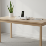 Modern minimalist home office scene with a sleek universal multi-device charging station on a light oak wooden desk, charg…