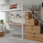 Modern compact bedroom with a white loft bed with study desk underneath, a young woman organizing bo