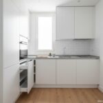 Modern compact kitchen in a small apartment, sleek white cabinets, built-in appliances, clever stora