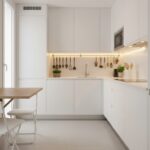 Small galley kitchen beautifully organized with white cabinets reaching to ceiling, fold-down breakf
