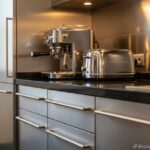 Close-up of stainless steel kitchen cabinets and drawer handles, with a coffee machine and toaster o