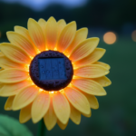 Close-up macro detail of a single yellow sunflower-shaped solar garden lamp at twilight, LED glowing