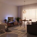 Small living room with beautiful layered lighting: warm floor lamp next to reading chair, pendant li