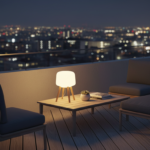A modern terrace at night with a designer portable outdoor lamp placed beside lounge chairs and a lo