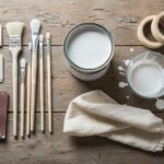 Flat lay of wood patina DIY supplies on a rustic wooden table: white acrylic paint can, different br