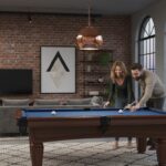 Elegant home entertainment room with a beautiful dark wood pool table with blue felt, a couple playi