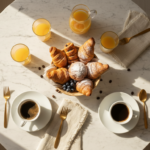 Close-up overhead view of a round marble dining table with breakfast setting, fresh pastries, coffee