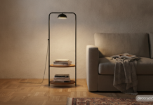 Lámpara estantería para libros: cómo elegir un 2 en 1 que ilumine de verdad Lámpara estantería para libros de acero negro junto a un sofá de lino gris en un salón iluminado con luz cálida